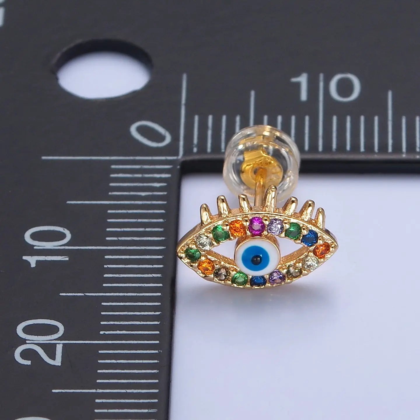 Colorful stone earring next to ruler.