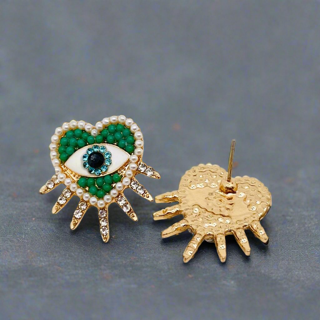 Closeup of heart shaped beaded stud earrings showcasing a vibrant color combination with green, light blue, and pearl. Earrings have spikes coming out of the bottom of the hearts with cubic zirconia accents.
