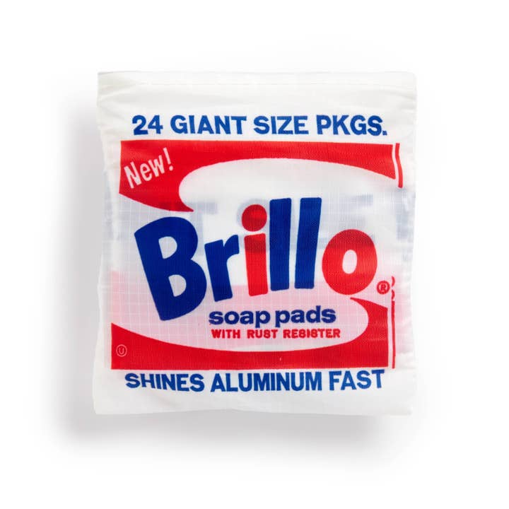 Close-up view of a reusable tote bag with Andy Warhol's Brillo soap pads design. The bag displays the classic Brillo logo in red and blue on a white background, mimicking the appearance of Brillo packaging.