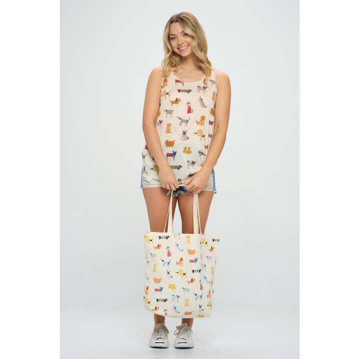 Full view of a model holding a tote bag with a whimsical dog pattern, showcasing playful, detailed illustrations of dogs against a light background.