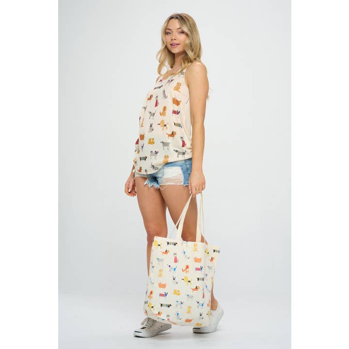 Full view of a model holding a tote bag with a whimsical dog pattern, showcasing playful, detailed illustrations of dogs against a light background.