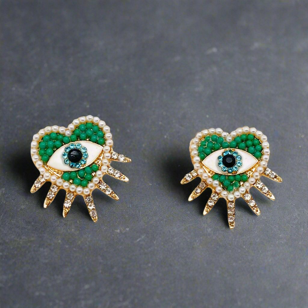 Closeup of heart shaped beaded stud earrings showcasing a vibrant color combination with green, light blue, and pearl. Earrings have spikes coming out of the bottom of the hearts with cubic zirconia accents.