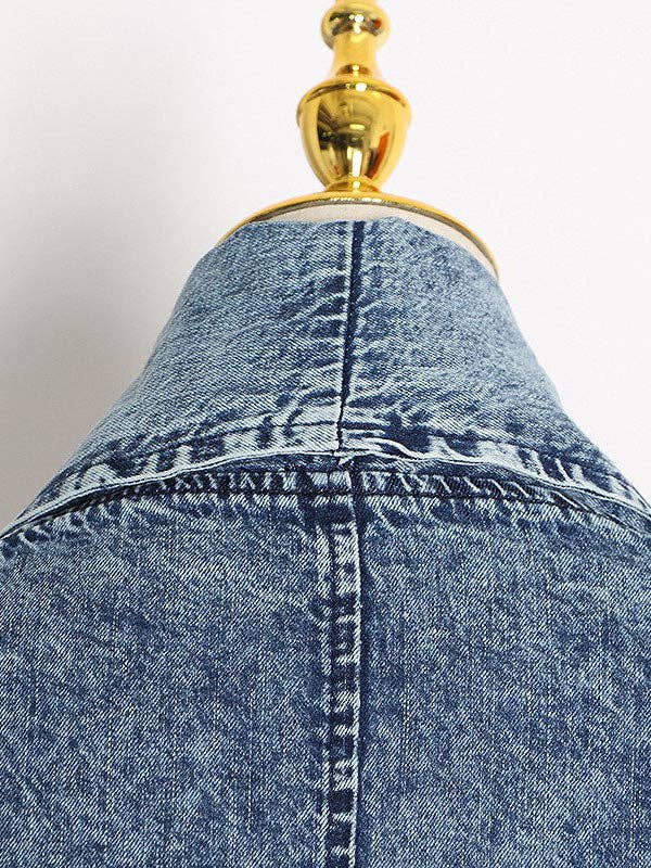 Close up of the back of an oversized denim jacket with 3/4 sleeves and large pockets, offering a relaxed fit and stylishly casual vibe.