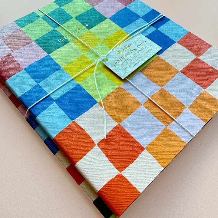 Angled view of a notebook duo. Colorful, rainbow checked design.
