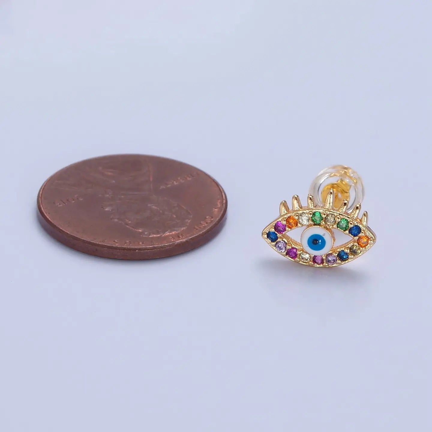 Colorful evil eye earring next to penny for size comparison.