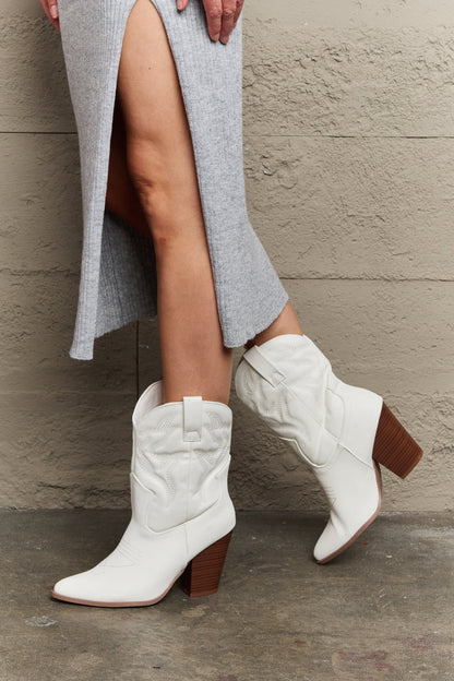 Side view of model wearing White mid-calf cowboy boots featuring a low heel and classic western-inspired design. These boots offer a perfect blend of style and comfort, adding a bold yet versatile touch to any outfit.