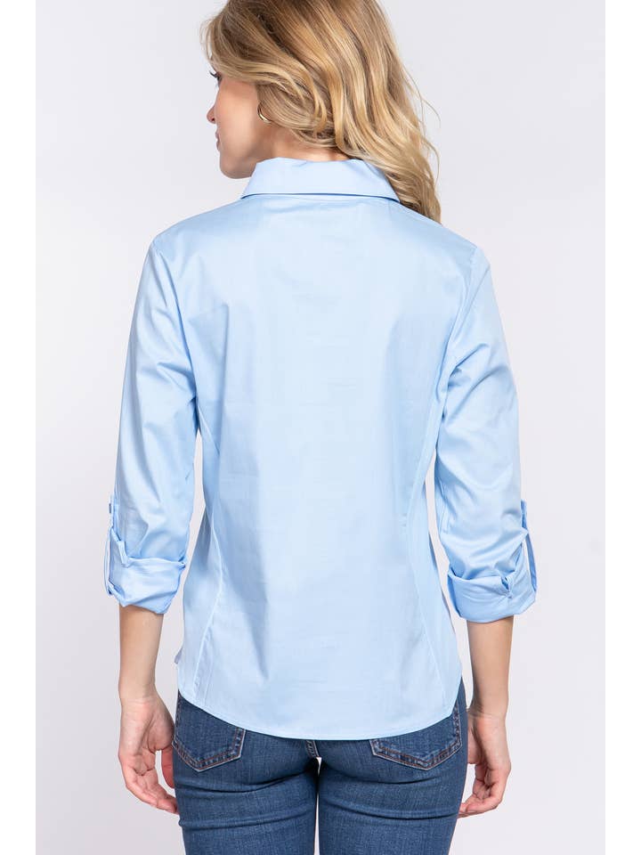 Closeup back view of a woman wearing a light blue button-down shirt with 3/4 roll-up sleeves and skinny jeans, showcasing a casual yet polished look perfect for both work and casual settings. 