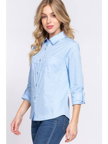 Closeup side view of a woman wearing a light blue button-down shirt with 3/4 roll-up sleeves and skinny jeans, showcasing a casual yet polished look perfect for both work and casual settings. 