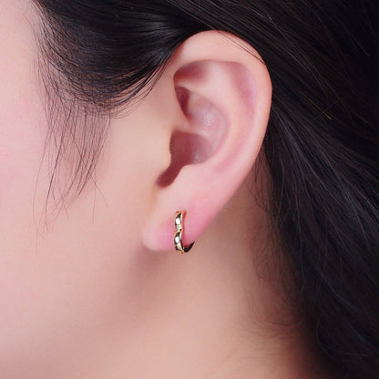 Close-up of a woman's ear wearing a 24K gold-filled heart-shaped huggie hoop earring.