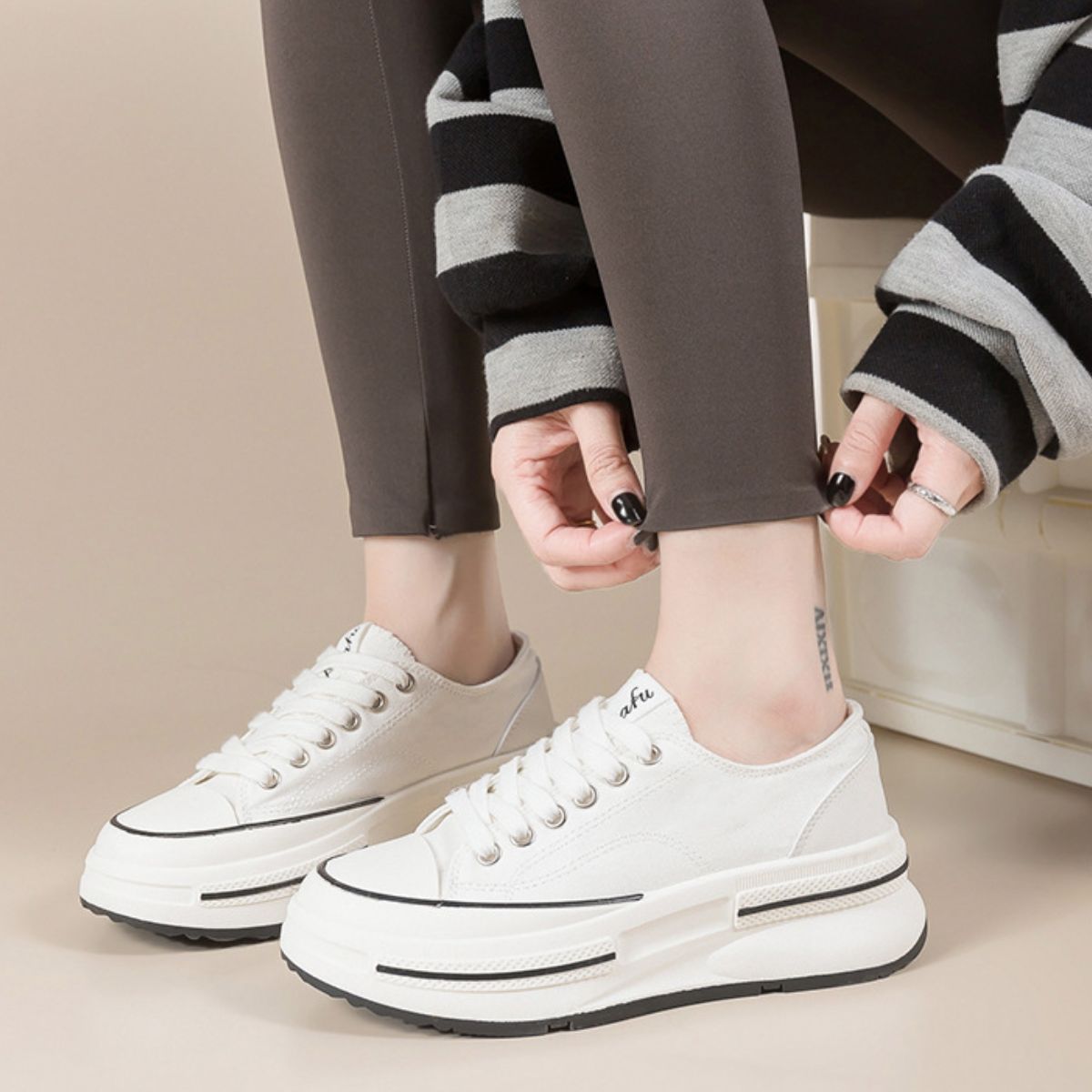 Model wearing Ivory Tied Round Toe Platform Sneakers crafted with elastomer and polyester, combining versatility and trendiness. These imported sneakers elevate any look with their sleek and modern design.