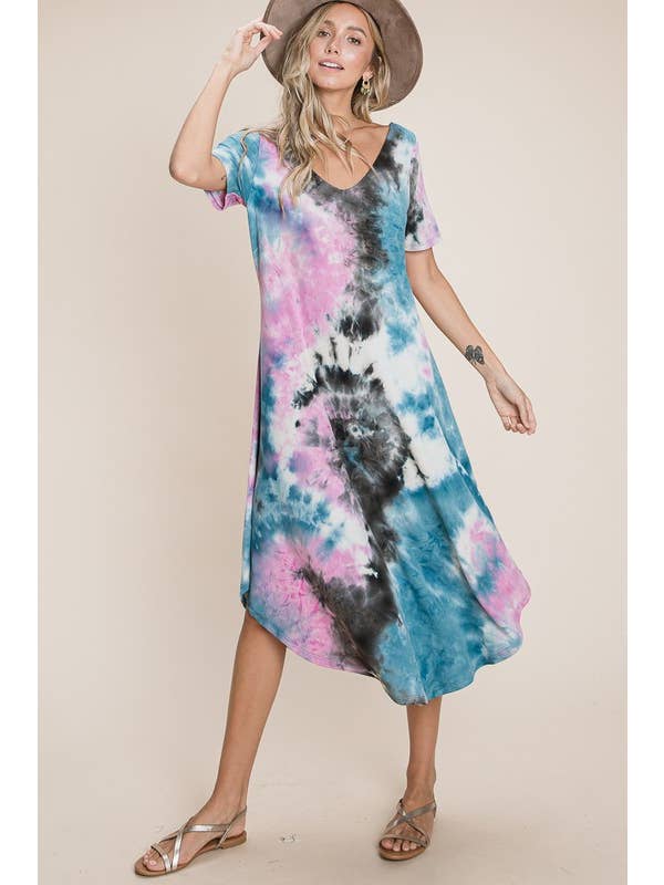 Woman wearing a blue and pink tie-dye V-neck dress with short sleeves, posing confidently with a hat.