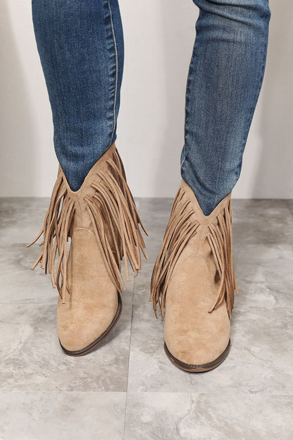 Front view of model wearing stylish ankle boots featuring fringe detailing, embodying cowboy-inspired fashion. With a point toe and high heel height of 2 inches, these boots blend rugged charm and feminine elegance. Imported and designed for a modern twist on the classic cowboy look, they are a versatile addition to any wardrobe.