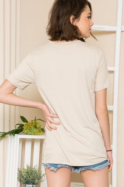 Woman wearing a beige short-sleeve top and denim shorts, facing away from the camera.