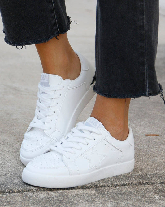 Close-up of a woman wearing Star Sneakers with frayed black jeans.