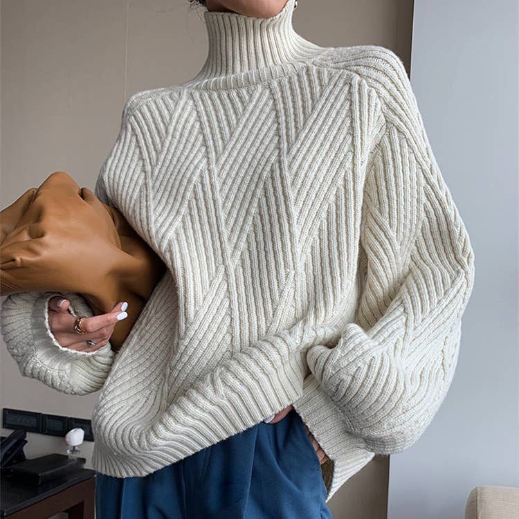 Woman wearing a white turtle neck long sleeve pullover sweater with blue trousers, holding a brown clutch.