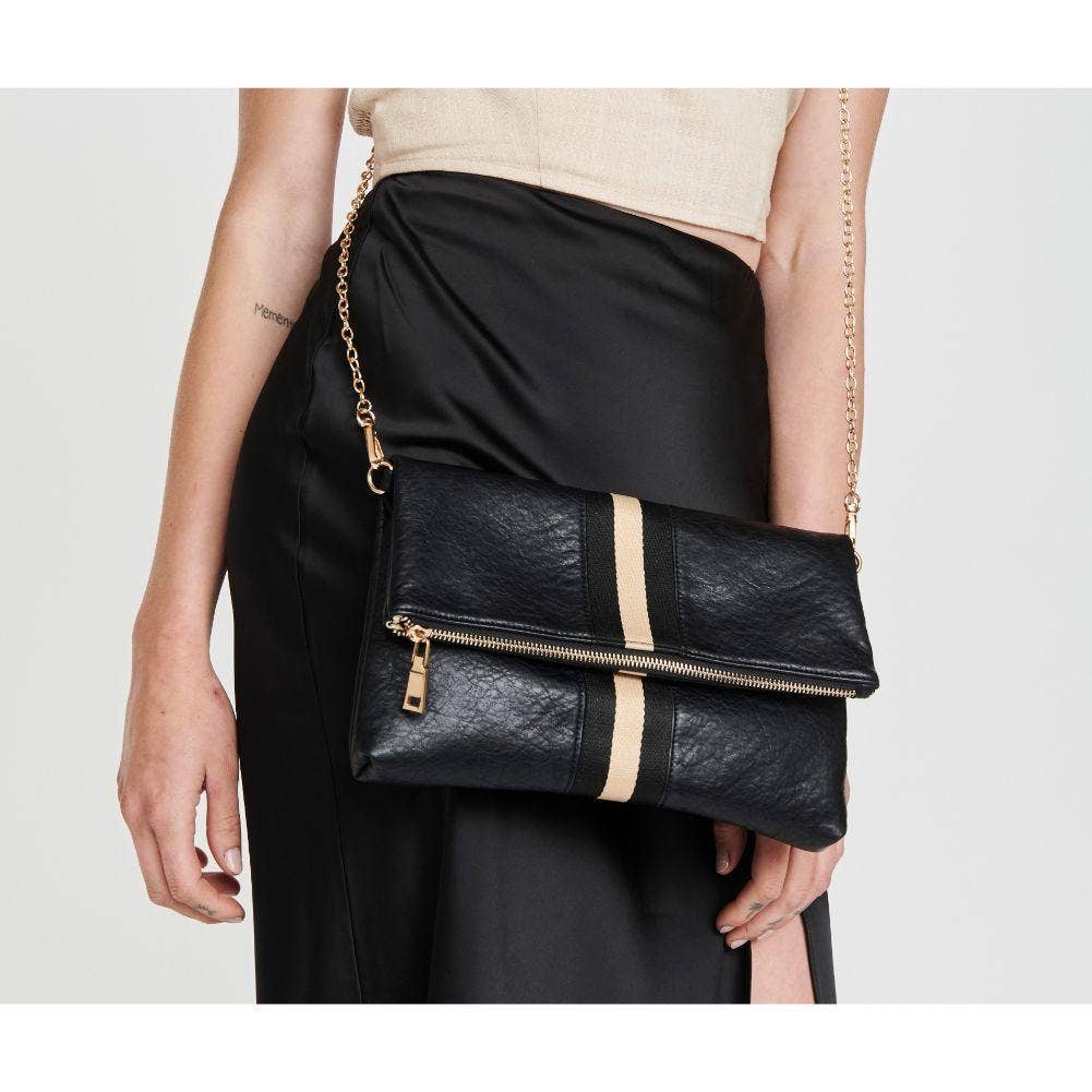 Model posing with the black fold-over clutch with a gold stripe, paired with a beige top and black skirt, demonstrating a chic outfit idea.