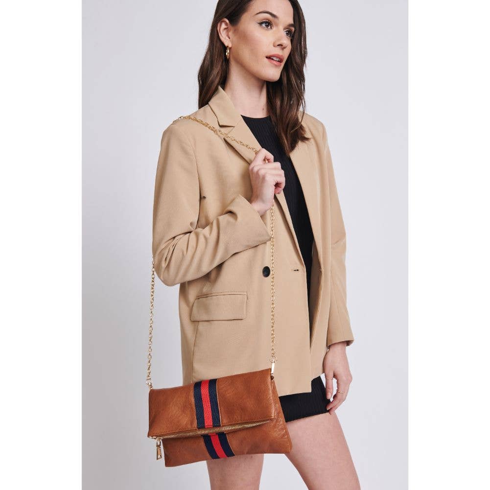 Model wearing a beige blazer and black dress, holding a brown fold-over clutch with a red and navy stripe, featuring a gold chain strap.