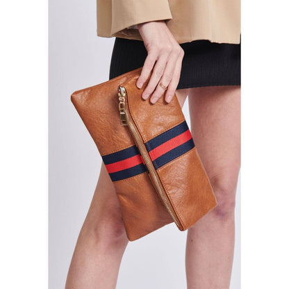 Close-up of the brown fold-over clutch with a red and navy stripe, being held by a model in a beige blazer and black dress.