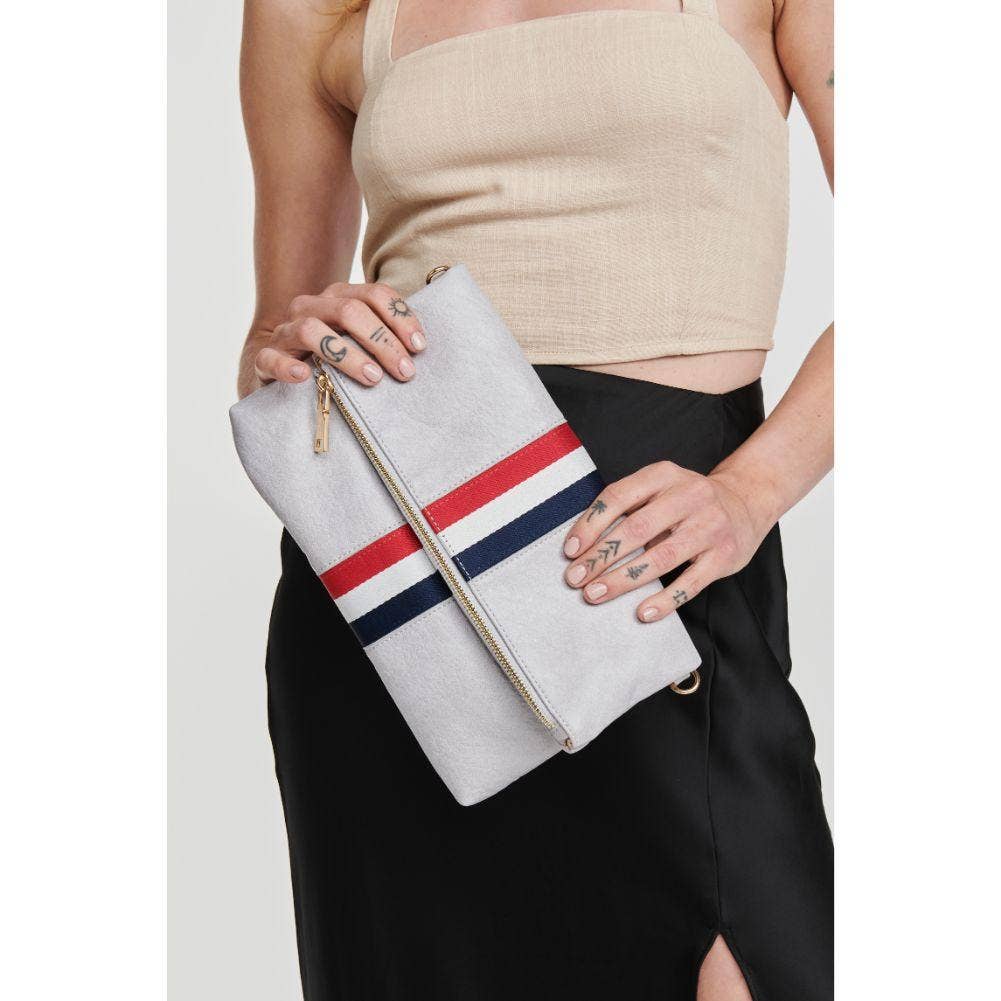 Model wearing a beige top and black skirt, holding the gray fold-over clutch with a red, white, and blue stripe as a crossbody bag with a gold chain strap.