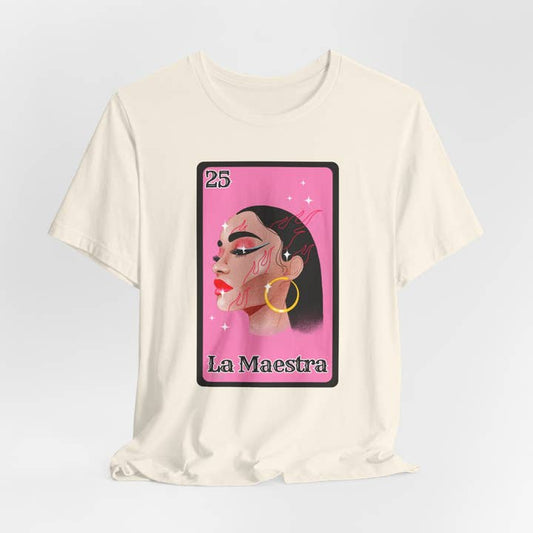 A spread-out La Maestra Lotería-Inspired T-Shirt laid flat on a rustic surface. The vibrant design prominently features the number 25 and a beautifully illustrated Latina woman, symbolizing "La Maestra." The shirt's soft, high-quality cotton fabric is visible, highlighting its comfort and durability.