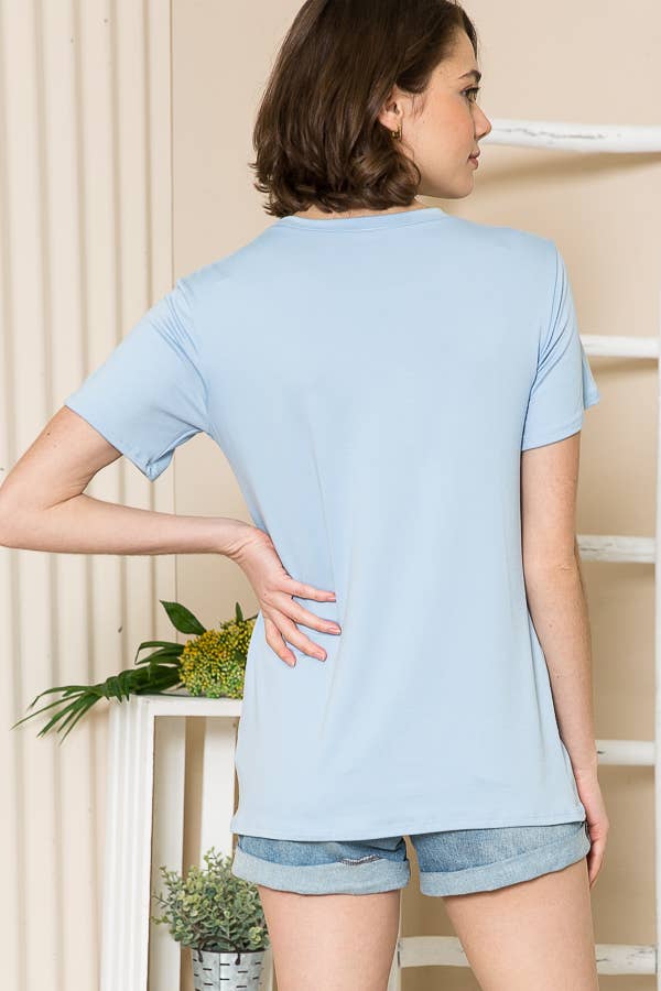 Model wearing a light blue short sleeve top, back view, paired with denim shorts.