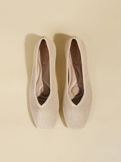 Top-down view of beige pointed toe flats with a V-cut design, showcasing the inner padding.