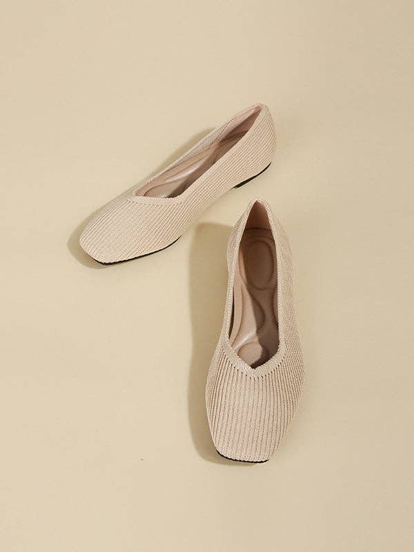 Top view of a pair of beige pointed toe flats with a V-cut design.